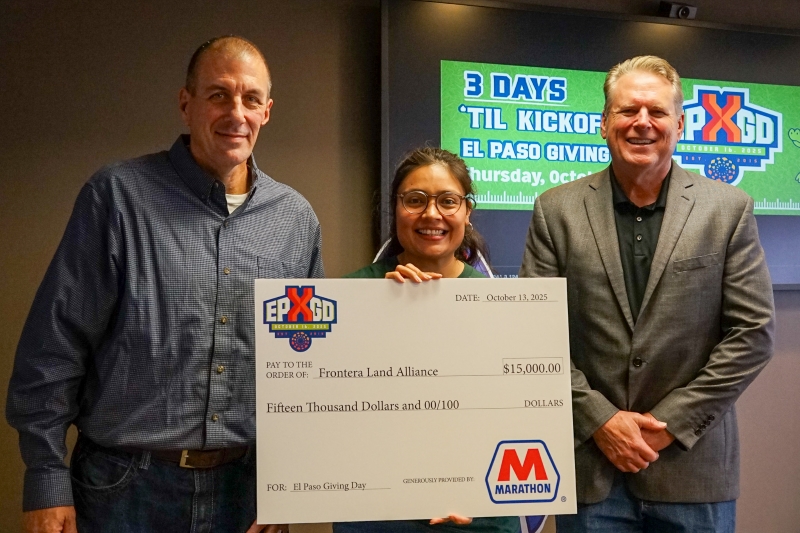 Three people standing next to each other with a cardboard check. 