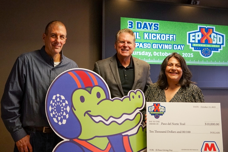 Three people standing next to each other with a cardboard check. 