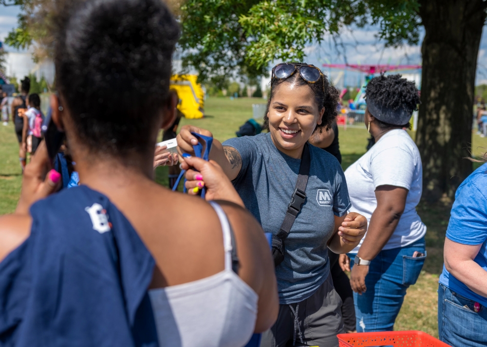 A person at an outdoor event handing a bag to another person.