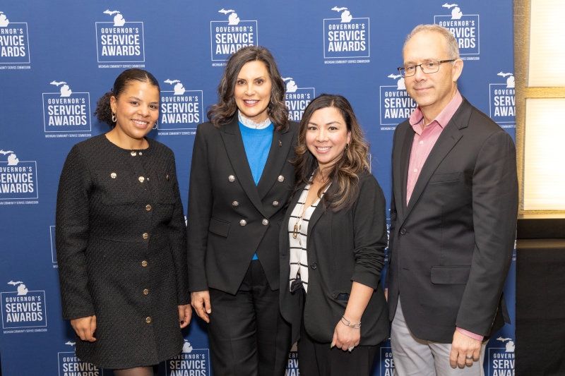Four people in front of a blue backdrop.