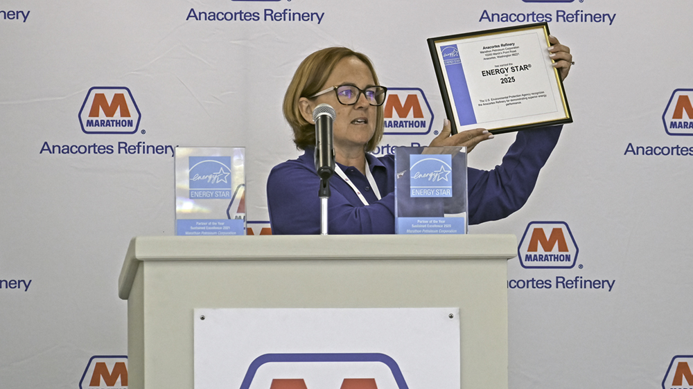 A woman at a podium holds up a framed certificate