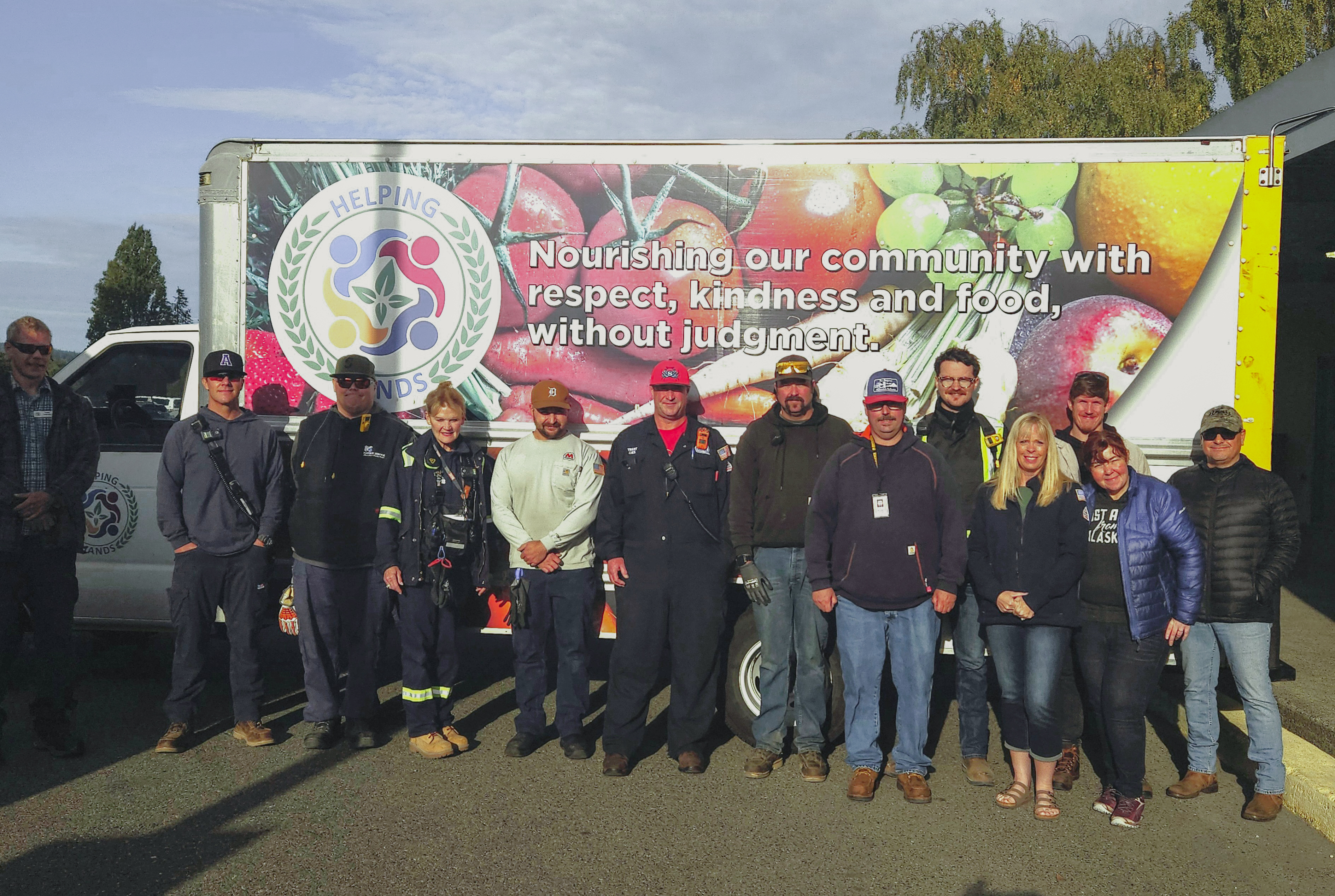 Employees stand together in front of a Helping Hands box truck.