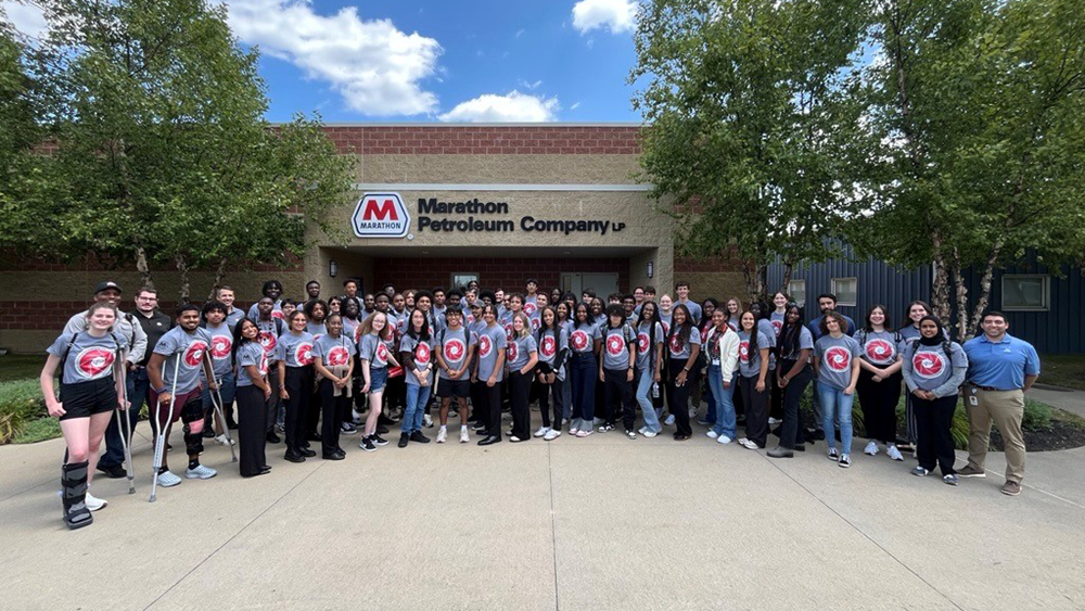  A group of people gather in front of a building for a photograph.