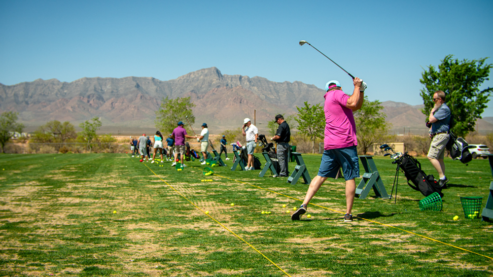 Golfers lined up practicing their swing.