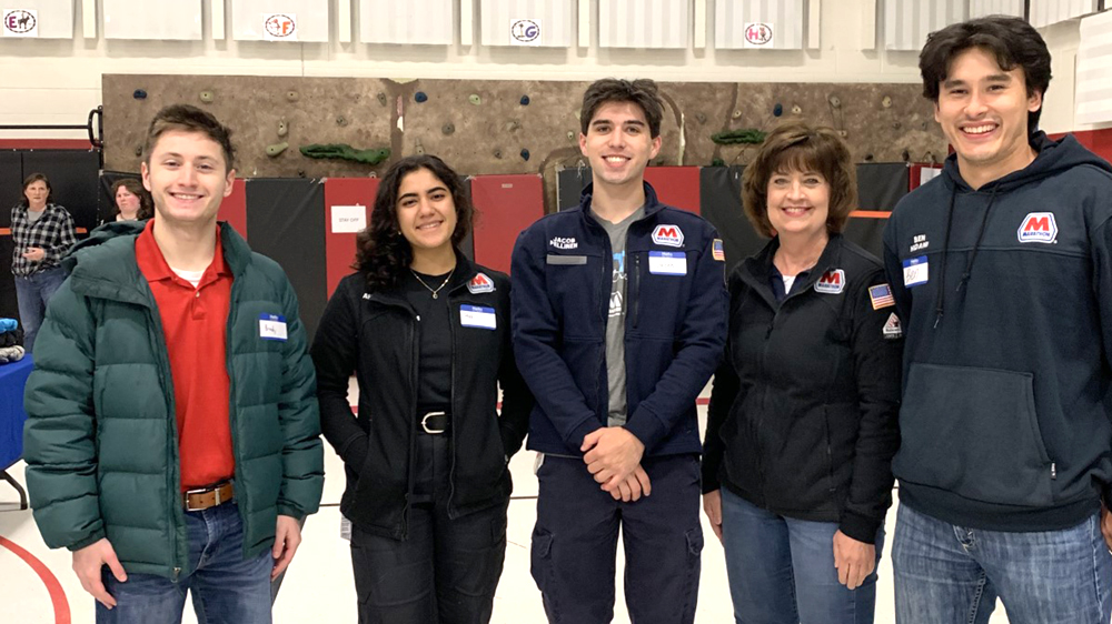 A group of adults stand together indoors.