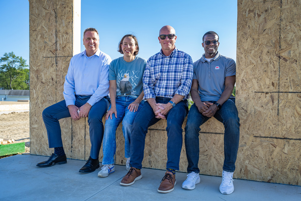 Four people sit in the window opening of a Habitat for Humanity home under construction in Findlay, Ohio.