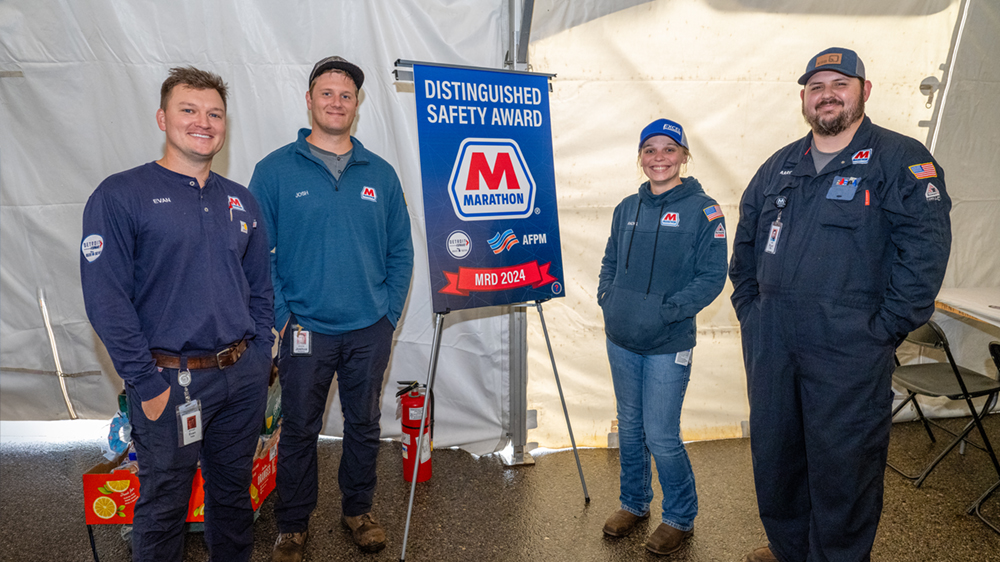 Four people in a tent with a sign that says Distiguished Safety Award.