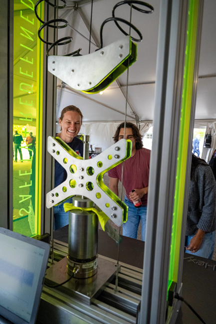 Two people watch a impact machine.