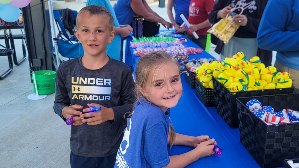Two children stand next to a table with baskets of trinkets.