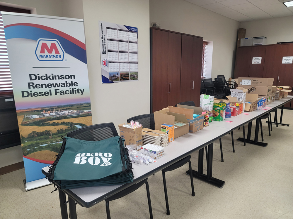 A table with assorted supplies set up in a room for packing care packages.
