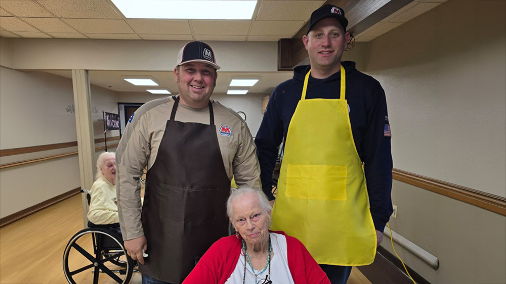Three people pose for a photo inside of a dining hall for an event.