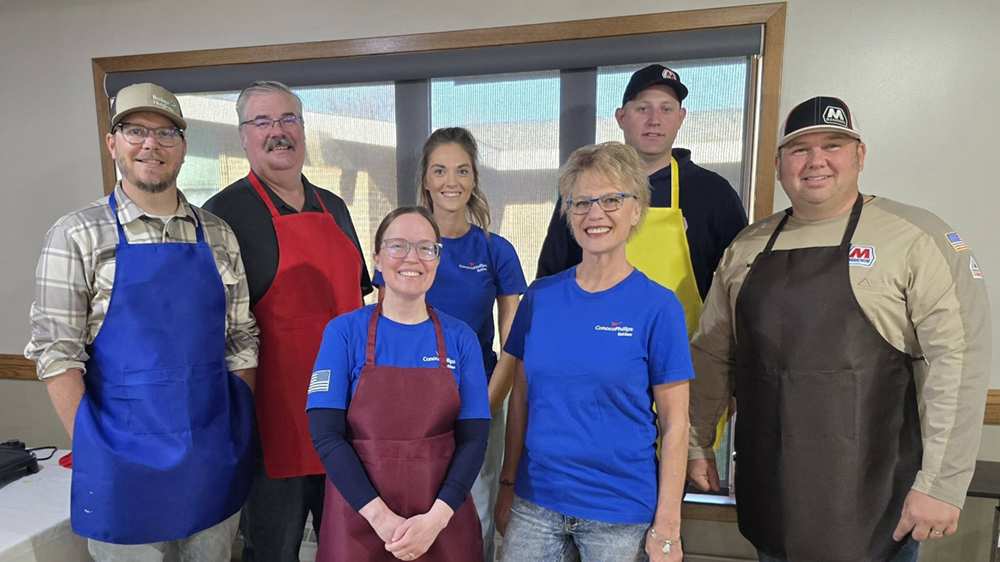 A group of volunteers wearing aprons pose together at a community event.