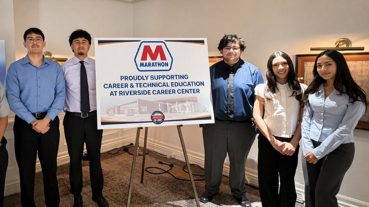 Young people standing next to a placard on an easel.&nbsp;