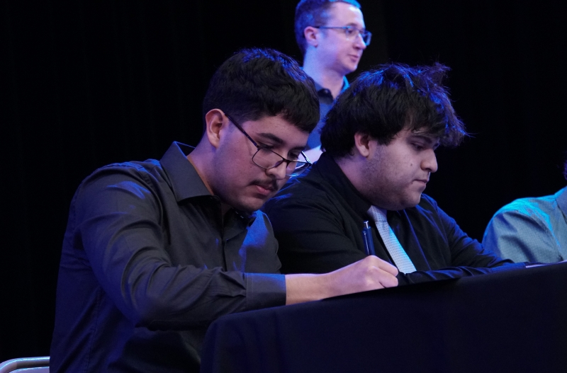  People writing as they sit at a table.