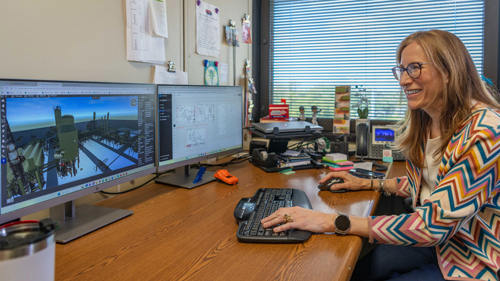A woman sits at a desk working on a computer.