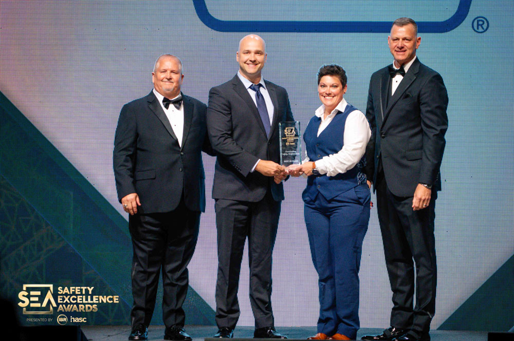 Four people stand on a stage holding an award during a banquet event.