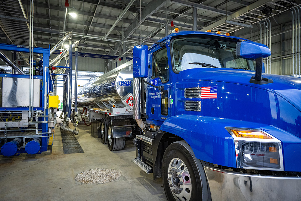 A transport truck cab and fuel tank trailer in a lane of a transport truck terminal.