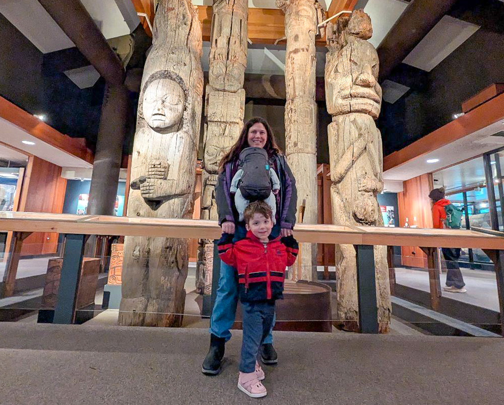 A woman stands in a museum with two children.