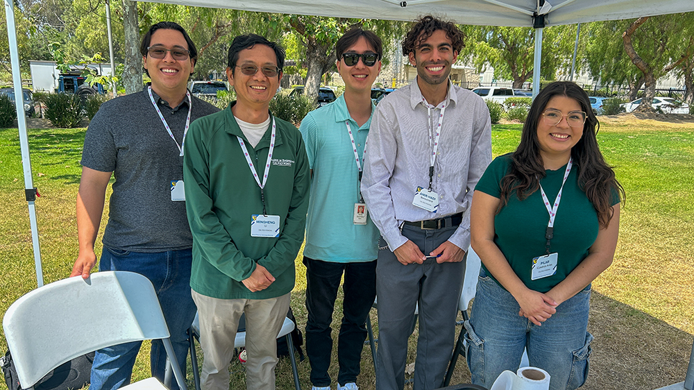 A group of people standing outside beneath a presentation booth.