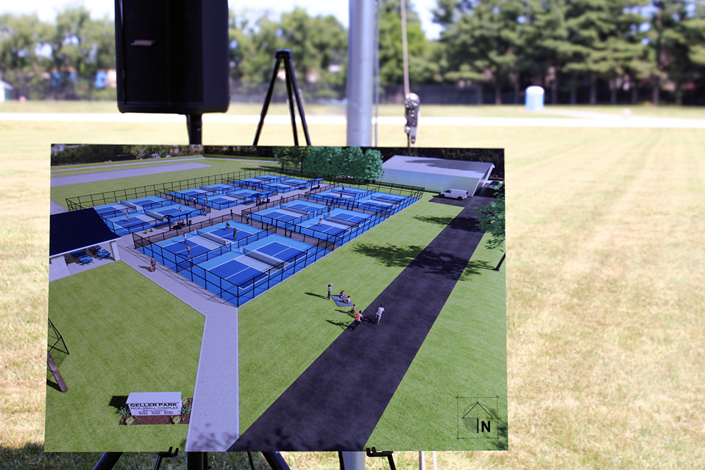 A photo of the park plans sits on an easel in front of a grassy field.