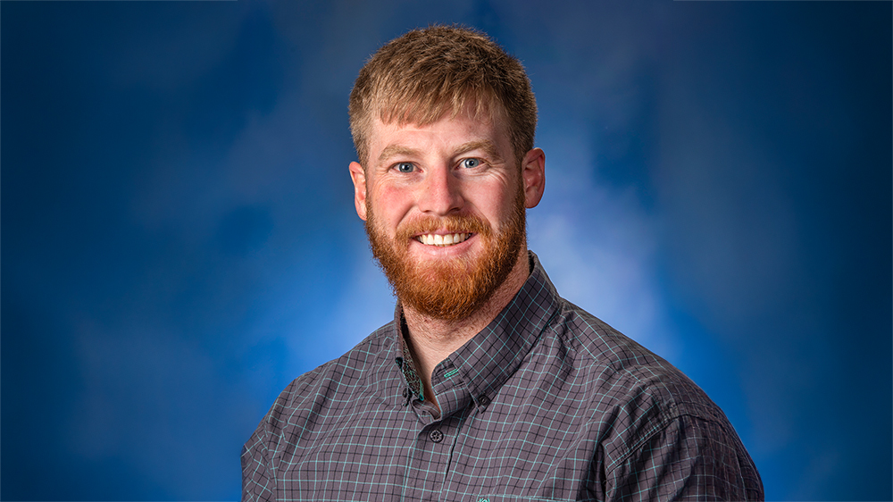 A professional headshot of a man smiling at the camera.