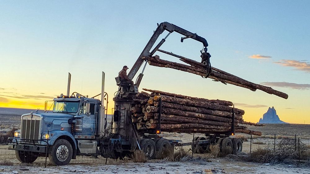 Pieces timber are unloaded from a large trailer. 