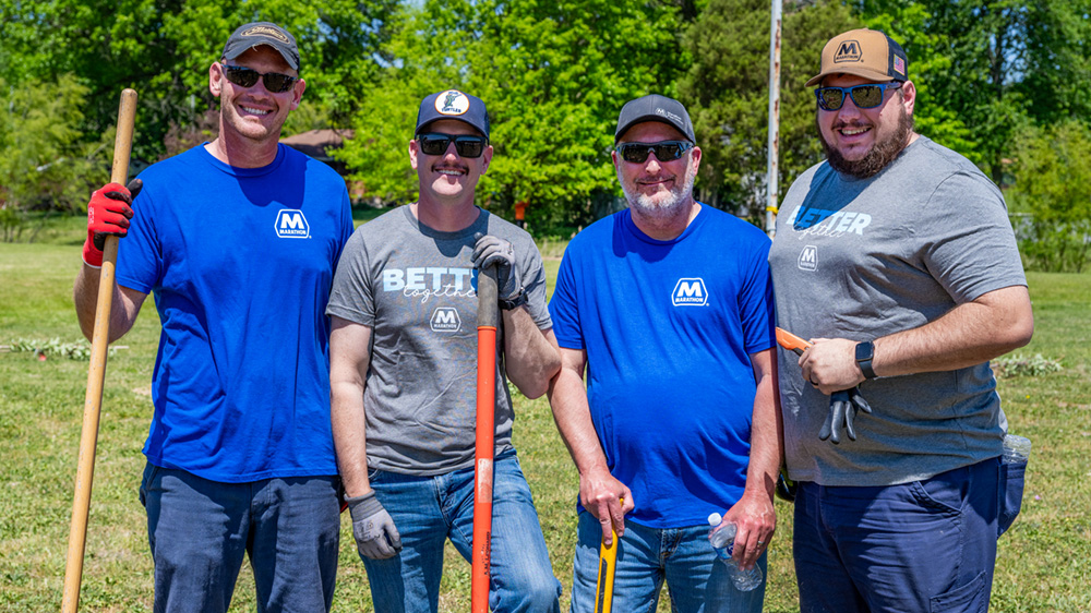 : A group of employee volunteers poses outdoors during a community tree-planting event.