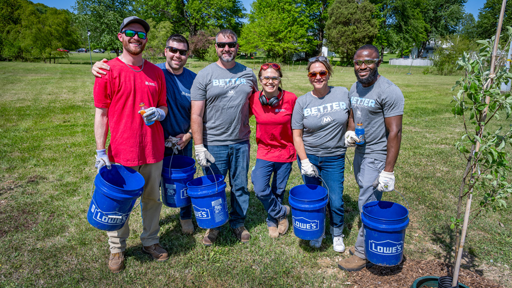 A group of employee volunteers pauses for a photo during an outdoor tree-planting event.