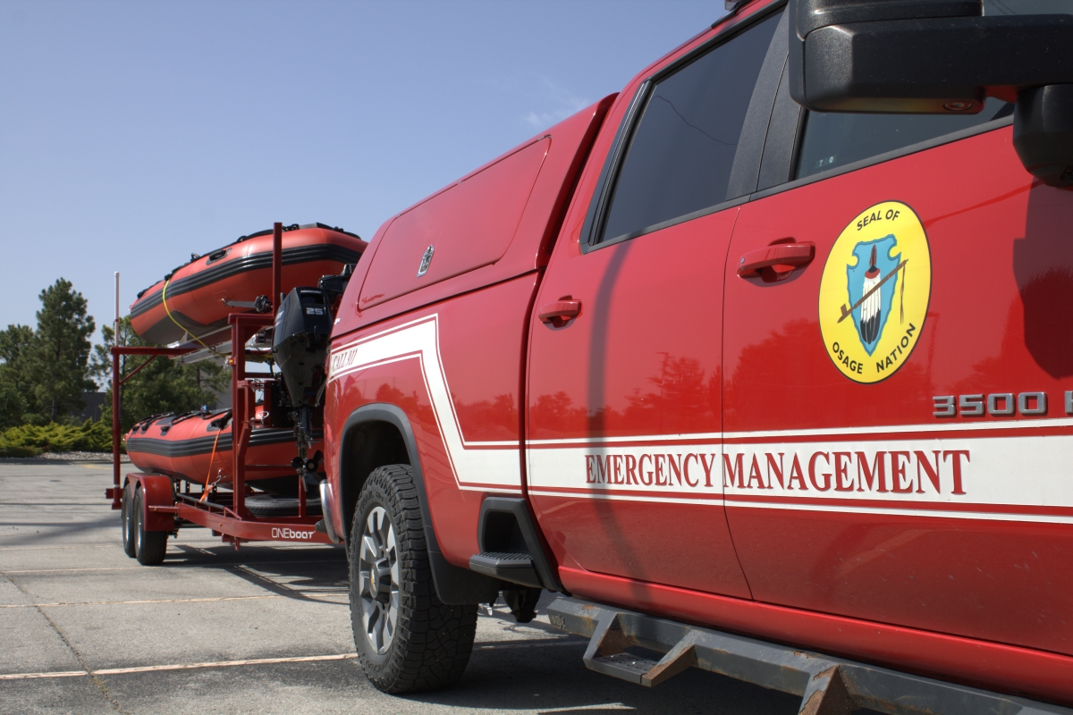 A pickup truck with an attached trailer that holds two pontoon rescue boats.