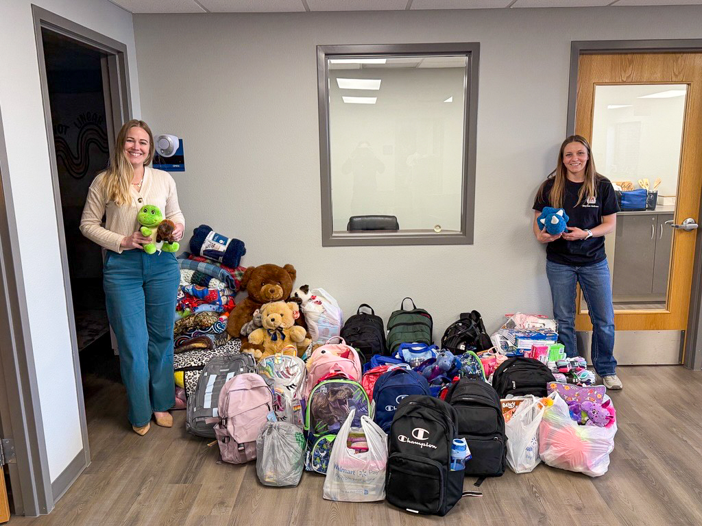 Two people standing beside a group of filled backpacks