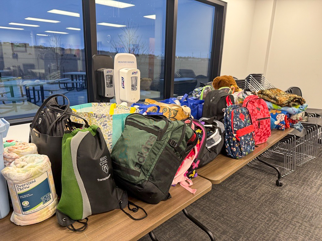 Group of filled backpacks and donated items collected by employees.
