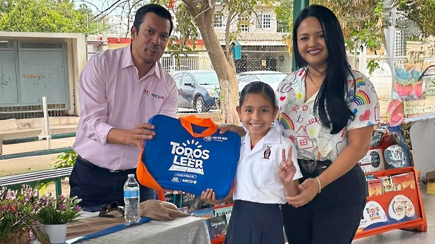 Two adults stand next to a young student who is holding a tote bag.