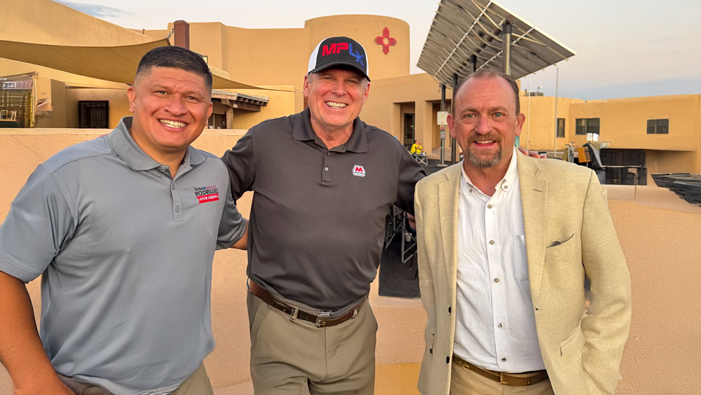 Three men standing together outside a building. 