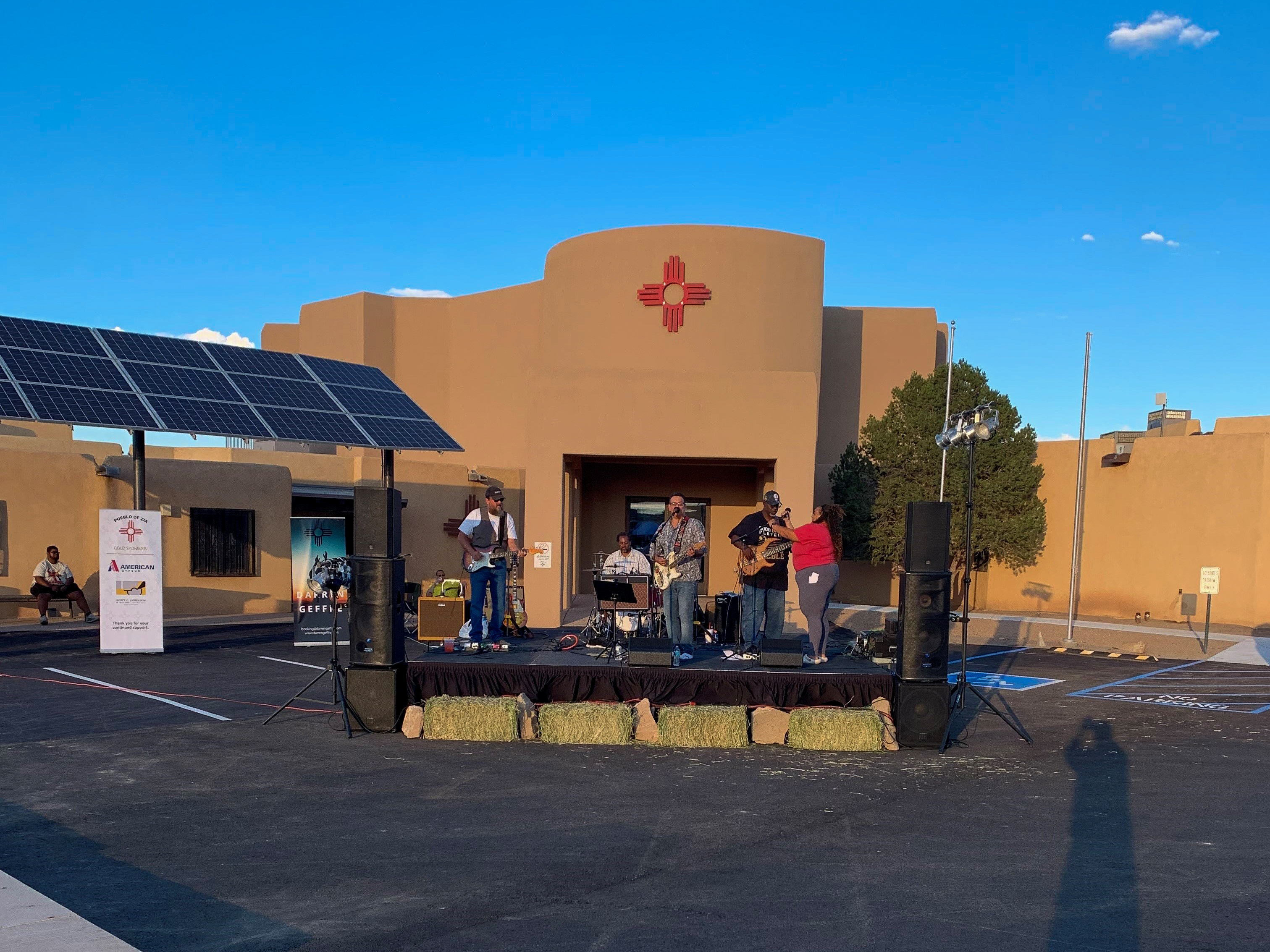 A band performs on a stage in a parking lot.&nbsp;