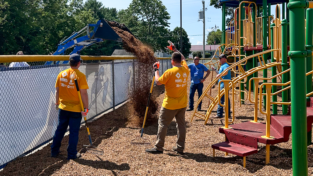 Volunteers spread mulch across a school playground.