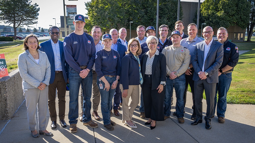 More than two dozen people stand together for a group photo outside during a groundbreaking event.
