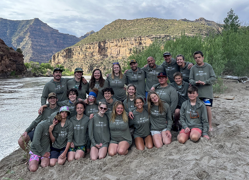 A group of people pose for a photo on the bank of a river. 