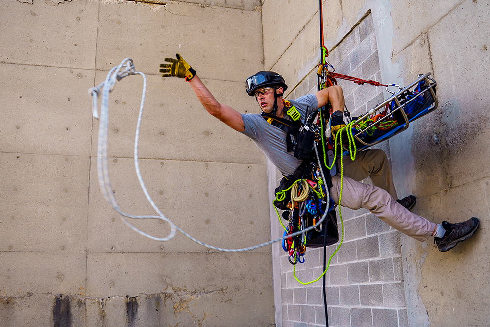 A man descends the side of a building using ropes and harnesses. 
