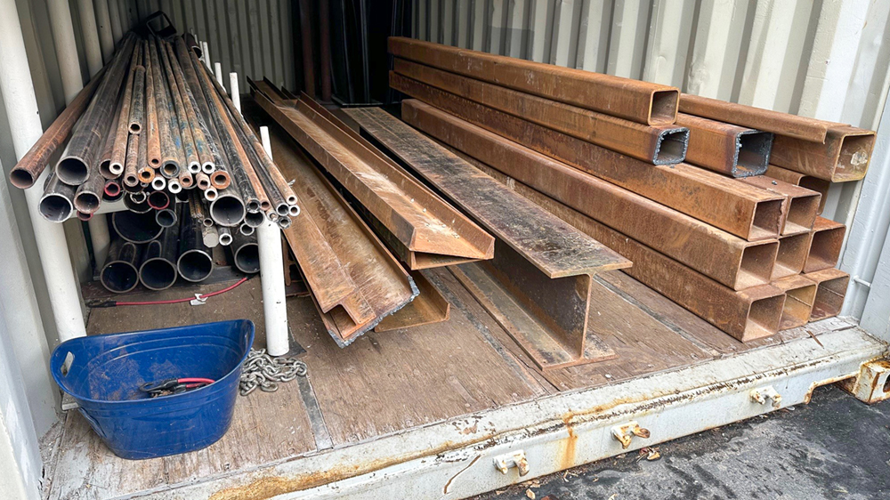 Stacks of metal pipes and beams in a delivery crate.