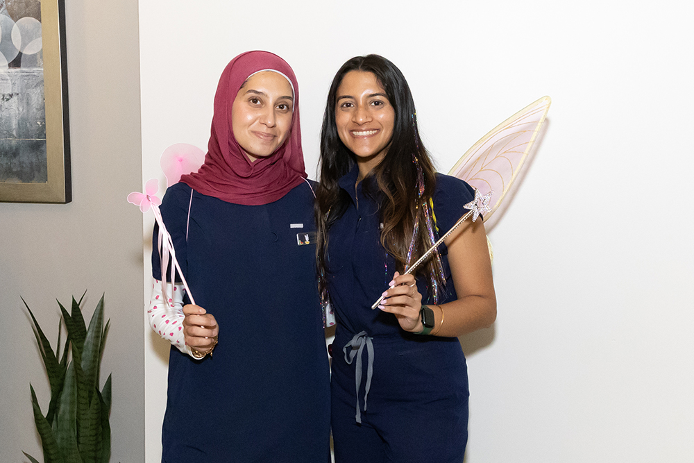 Two young women stand should to shoulder.