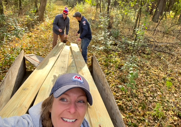 Three people standing together outside, smiling for a photo before a volunteer project.