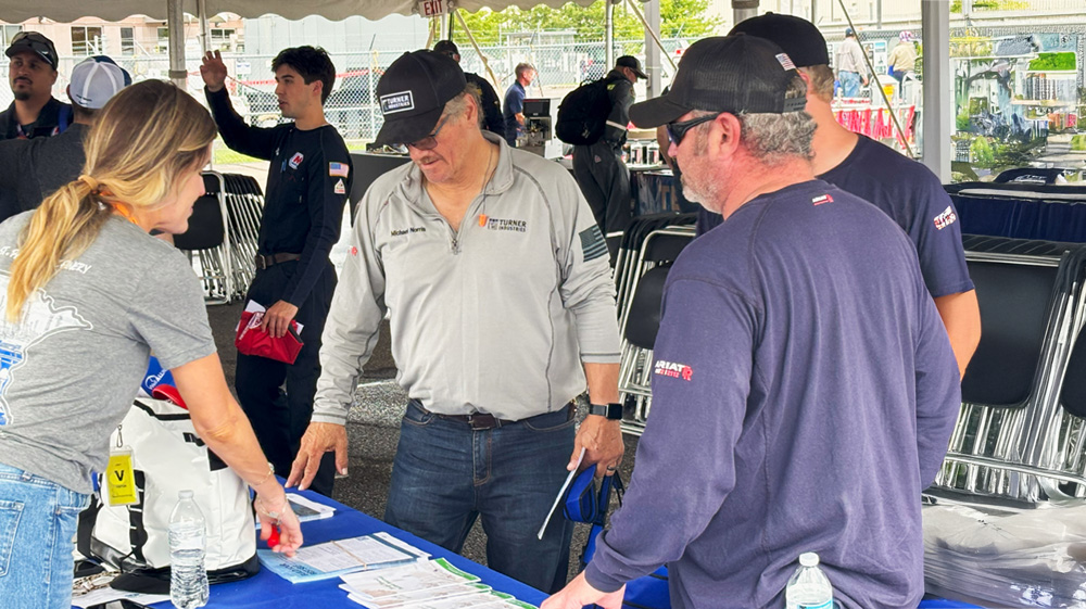 People in an event tent looking at flyers on a table.