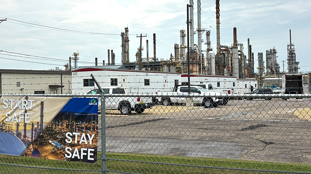 Photo of a fence with a refinery in the background.