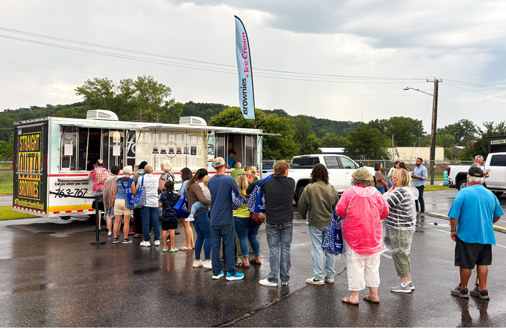 People waiting in line at a food truck during an outdoor event.