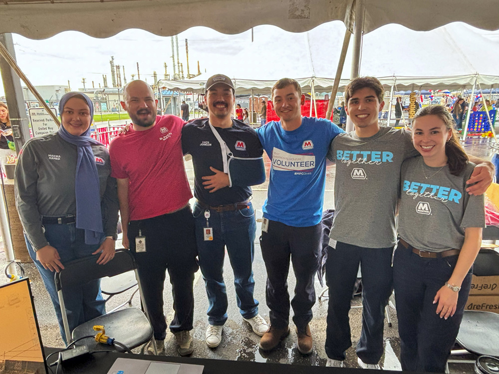 A group of people standing together under a tent, smiling for a photo.