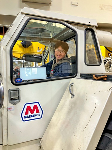 A person poses for a photo inside a work vehicle.