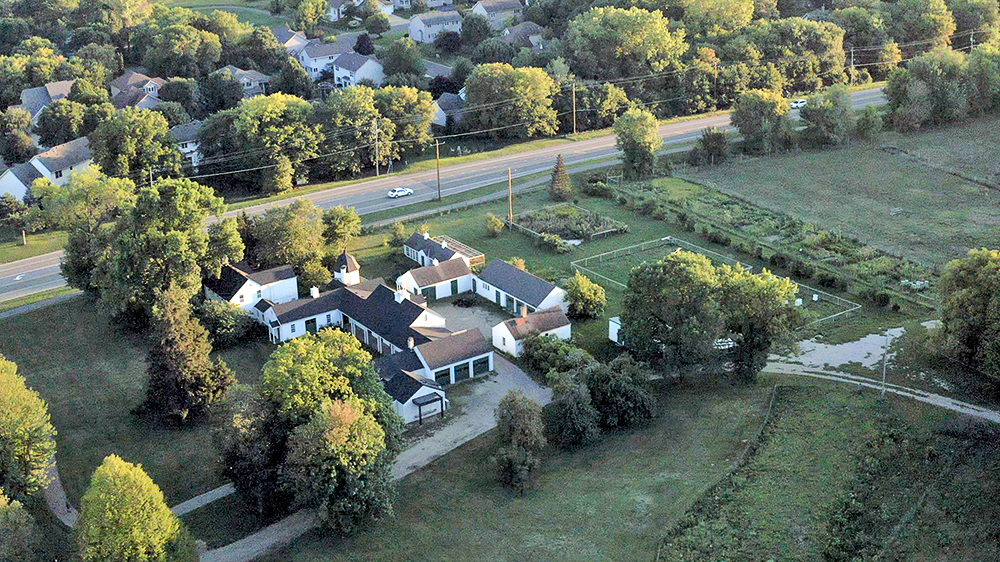 Aerial view of a farm with several buildings surrounded by trees.