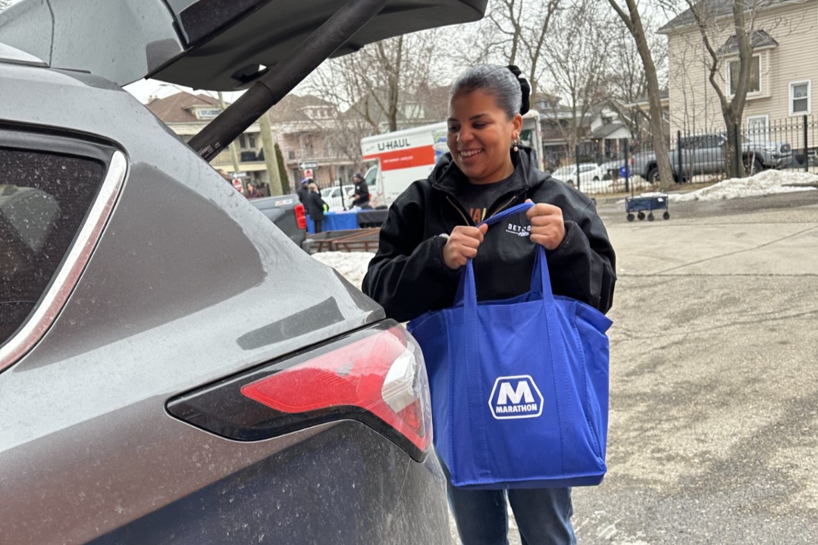  A person putting a blue Marathon bag into the back of a vehicle. 